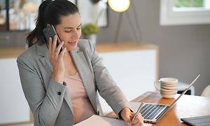 Woman talking on a phone and writing notes on a notebook