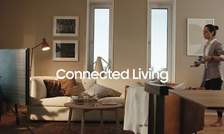 Samsung Connected Living - kvinde, der bærer smartphone og kaffekrus i stue