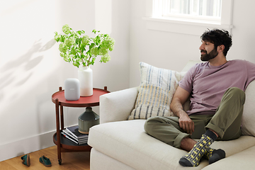 Mand sidder i sofa og lytter til noget på Google Nest Audio