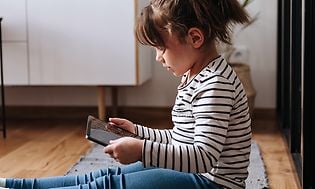 Pige der sidder på gulv med en tablet