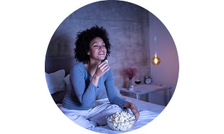 Kvinde spiser popcorn i en seng