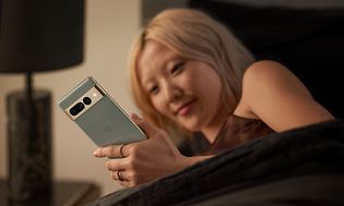 Kvinde ligger i sin seng og kigger på sin Google Pixel 7 Pro