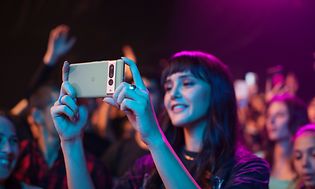 Kvinde, der står ved en koncert, der filmer på sin Google Pixel 7 Pro