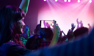 En kvinde til en koncert som filmer sangerinden med sin Google Pixel 7