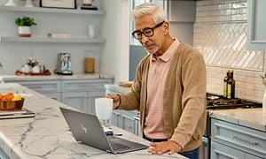 Google - Chromebook - En mand i et køkken holder sin kaffekop over sin HP 14 Chromebook
