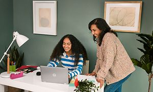 Google - Chromebook - En ung pige sidder ved sit skrivebord og bruger sin Dell Lattitude Chromebook with her mother next to her