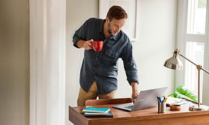 Google - Chromebook - mand med kaffekop rører ved sin Samsung Chromebook 4