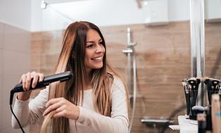 Kvinde på badeværelse bruger glattejern