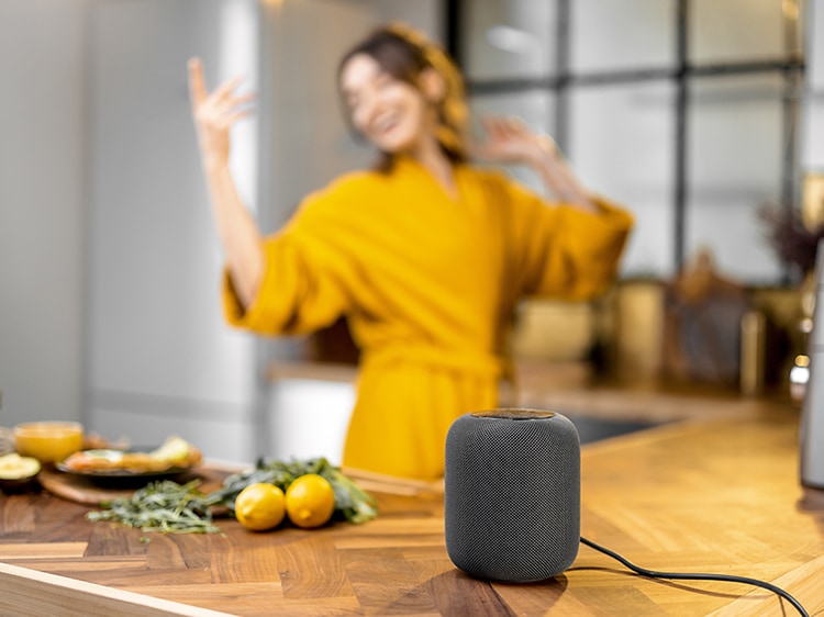 Smart højttaler på køkkenbordplade og en kvinde i baggrunden
