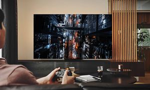 En fyr spiller videospil på sit Samsung Neo QLED Gaming TV med lav inputforsinkelse