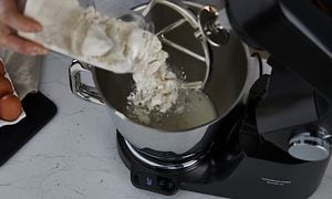 Billede af mel der er i gang med at blive hældt ned i skålen på en Kenwood Køkkenmaskine