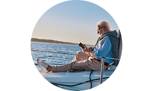 Mand sidder på en båd og kigger på smartphone