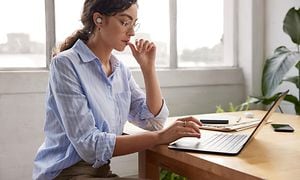 En kvinde der arbejder på sin laptop med Google Pixel Buds i ørerne