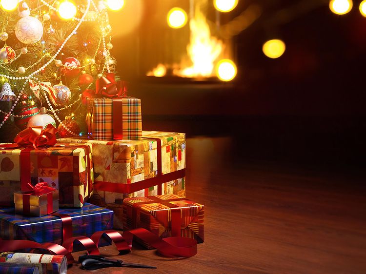 Juletræ med julegaver under i en stue med dæmpet lys
