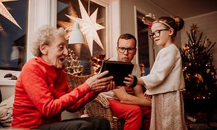 Billede af bedstemor der modtager en gave for barnebarn omgivet af familie i en julestue