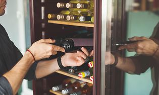 En person i færd med at tage en vin ud af et vinkøleskab