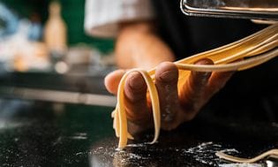 Kok i færd med at forme pasta med en pastamaskine