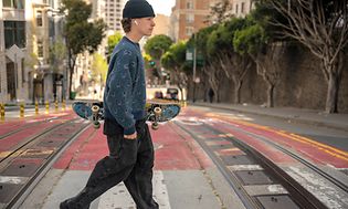 En mand med et skateboard og et JBL-headset i ørerne