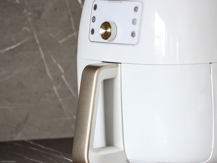 Nærbillede af en hvid airfryer på et køkkenbord