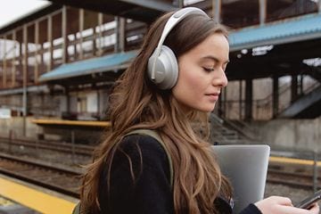 Kvinde med hovedtelefoner på en togstation