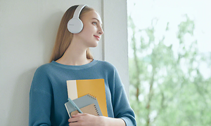 Kvinde med Sony hovedtelefoner med notesbøger i hånden