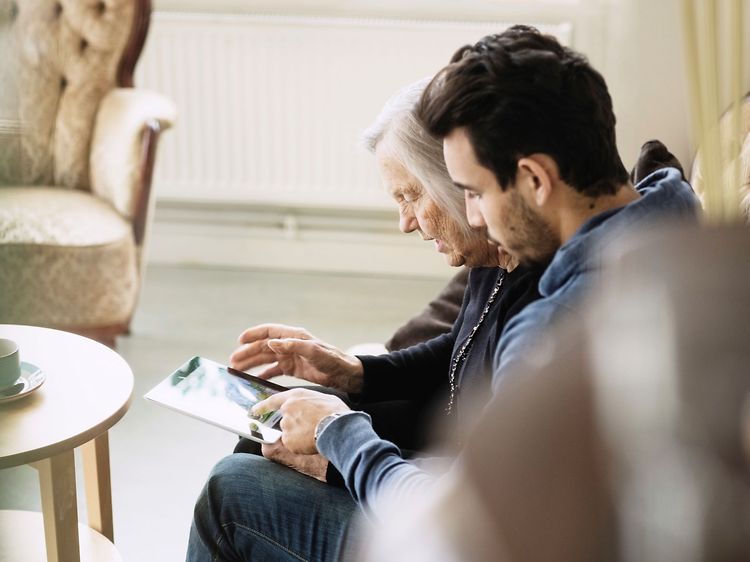 Billede af en ældre mand og en yngre mand i gang med at kigge på en tablet