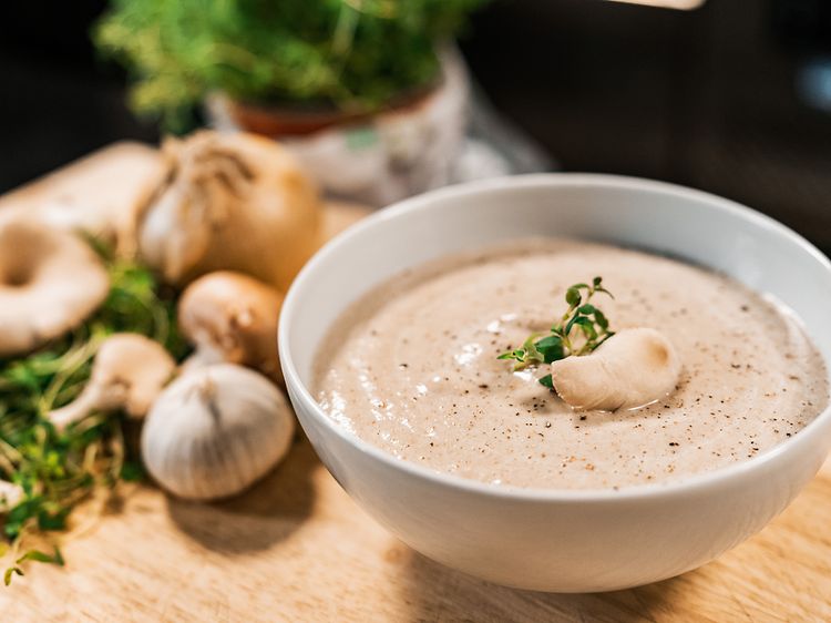 Grøntsagssuppe i en skål med løg og hvidløg ved siden af