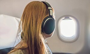 kvinde på et fly iført støjreducerende hovedtelefoner