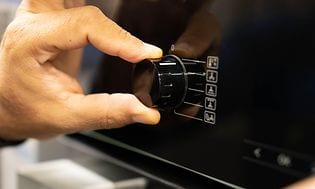 Billede af mands hånd der justerer på knappen på en ovn