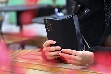 En person der holder en telefon i et cover på det bord