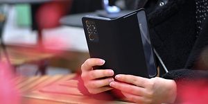 En person der holder en telefon i et cover på det bord