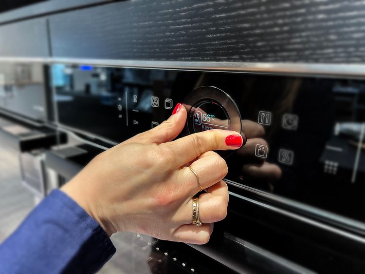 En hånd der justerer temperaturen på en ovn