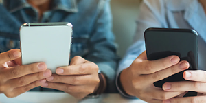 Telecom - skift telefoner - To teenagere der bruger deres telefoner ved et bord