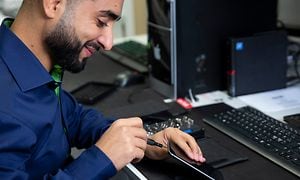 En smilende Elgiganten medarbejder, der reparerer en iPhone