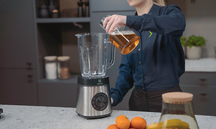 SDA - Blender - En kvinde der tilføjer væske til en fyldt blender