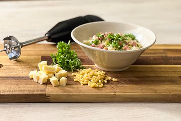 En sort stavblender ved siden af ingredienser og en skål