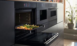 Bosch Accent line oven with the door open and a baking tray with vegetables 