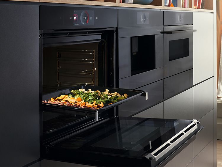 Bosch Accent line oven with the door open and a baking tray with vegetables