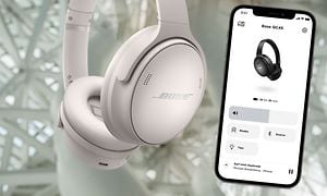 Hvide Bose høretelefoner ved siden af smartphone med Bose Music-appen på skærmen