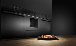 Bosch accent line ovne i Carbon black og en tallerken laks med grøntsager