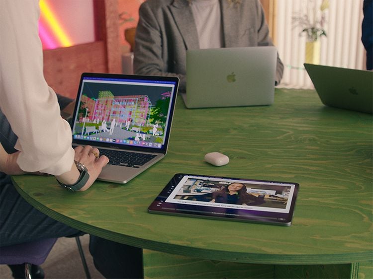 Grønt bord med MacBooks, iPad og Airpods