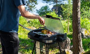 Elektrisk grill anvendes af mand i en have på en sommerdag