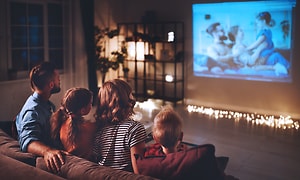 Hjemmebiograf med projektor: Familie, der ser en film gennem projektor på en skærm