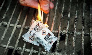 Hånd der antænder grillbriketter på en grill