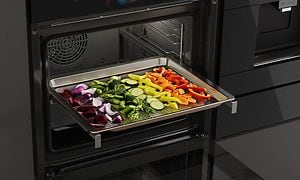 Steamed vegetables on a universal tray on their way into a Bosch accent line Series 8 oven