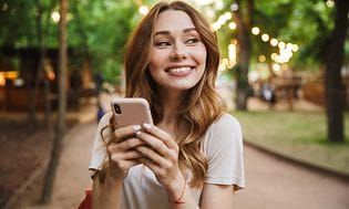  Smilende kvinde med smartphone i hænderne