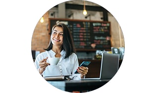 Kvinde med smartphone og laptop på en cafe