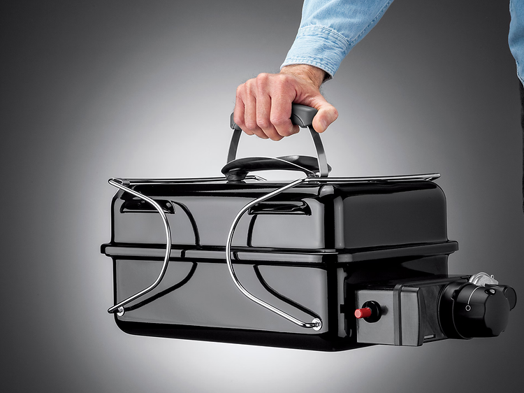 Mand der holder en transportabel grill