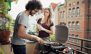 Par der står og griller ude på en altan 