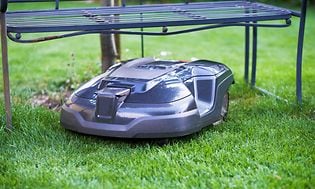 Robotplæneklipper der slår græs under en trampolin